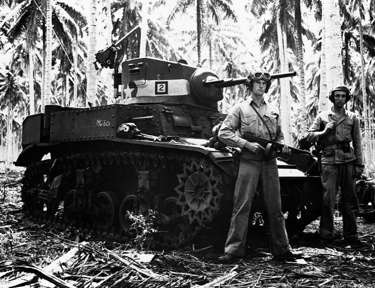 Two US Marines standing in front of an M3 Stuart in the jungle