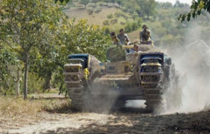 Members of the 1st Canadian Armoured Division driving a Churchill tank down a dirt road