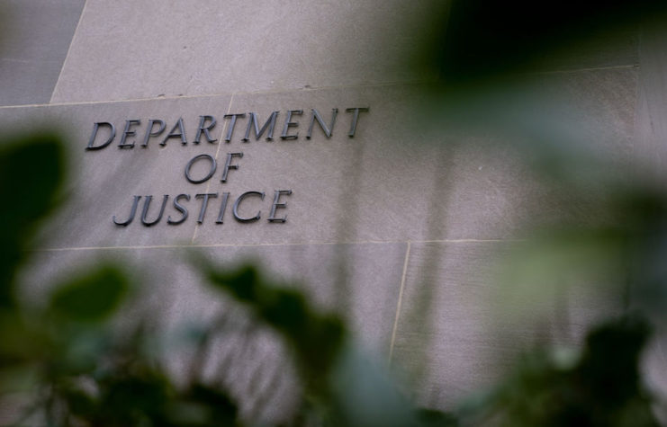 Exterior of the Department of Justice building, surrounded by greenery