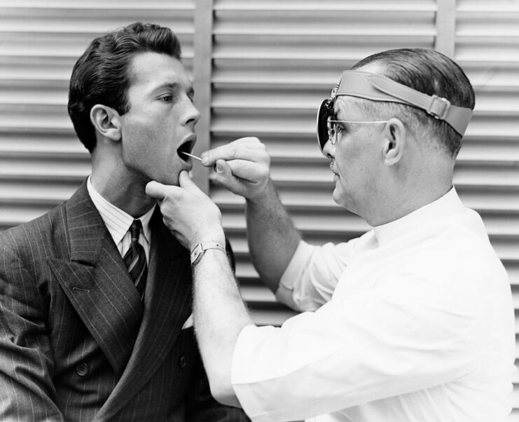 Doctor examining a male patient's throat