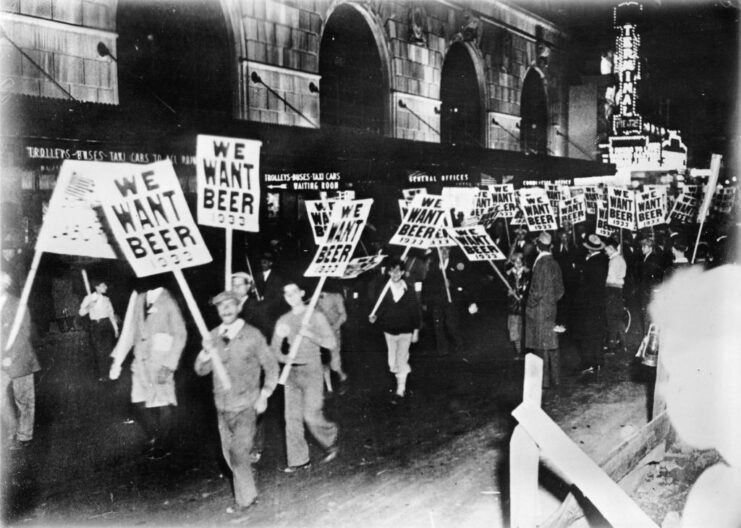 Protestors marching along a street holding signs that read, "WE WANT BEER"