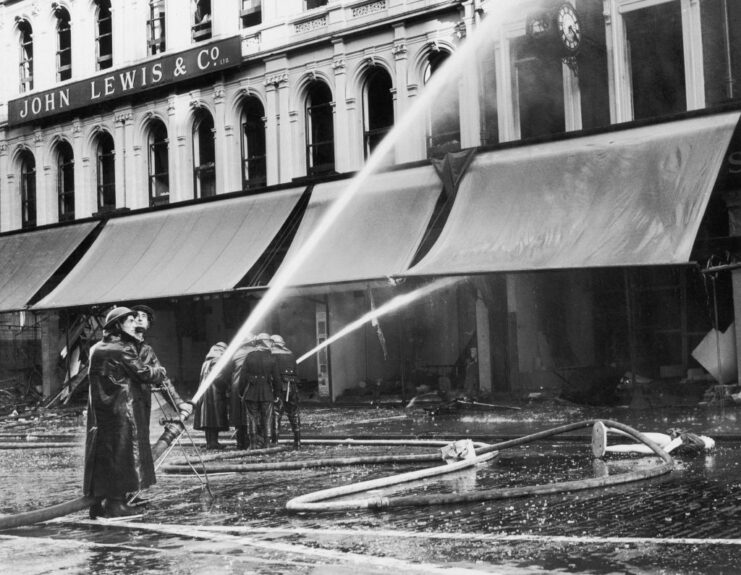 Firemen using a hose to put out a fire at a John Lewis & Co. store