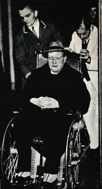 Winston Churchill being pushed in a wheelchair by two men