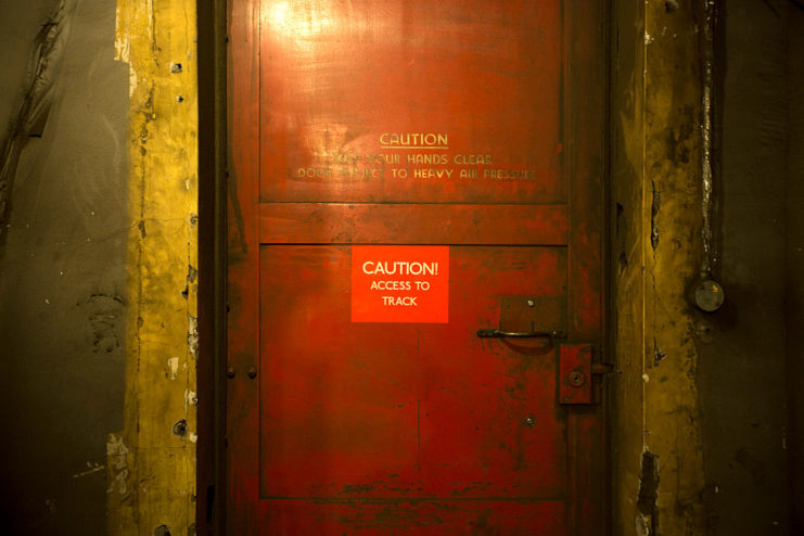 Red door with a sign reading "CAUTION! ACCESS TO TRACK" attached to it