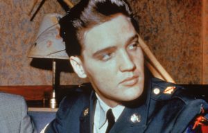 Elvis Presley sitting in his US Army uniform