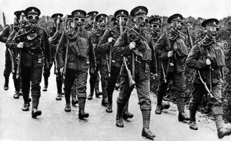 British troops marching together while wearing gas masks