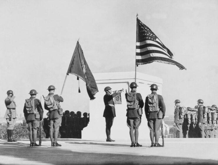 Troops standing at the Tomb of the Unknown Soldier, with an American flag flying nearby