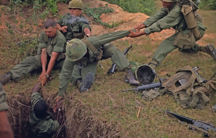 American soldiers lifting a comrade out of a Viet Cong tunnel