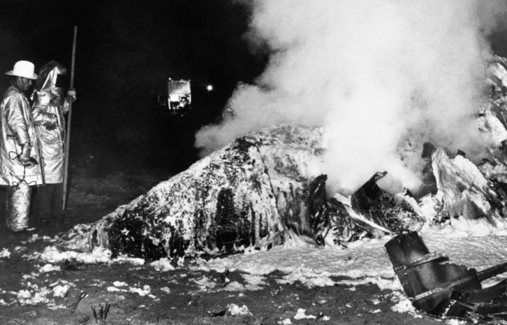 Firefighters standing around the smouldering wreckage of the B-52 Stratofortress