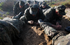 Navy SEAL trainees crawling through the dirt