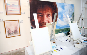 Photo of Bob Ross hanging behind easels