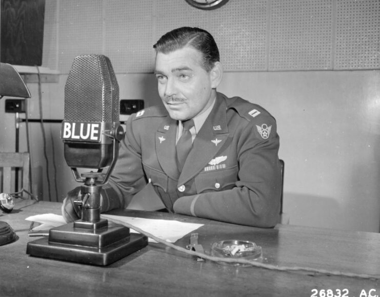 Clark Gable speaking into a microphone at a desk