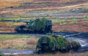 Two PzH 2000s driving through muddy land