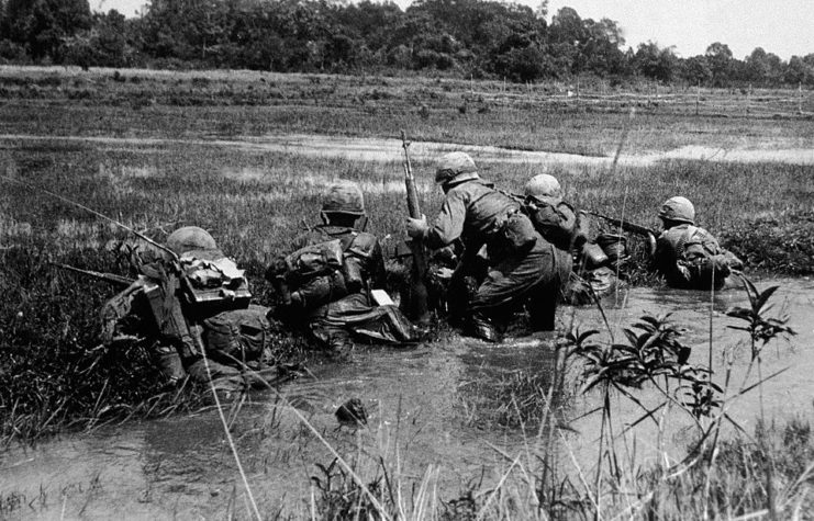 US soldiers climbing out of a stream