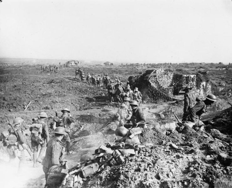 Australian infantrymen walking past camouflaged tanks