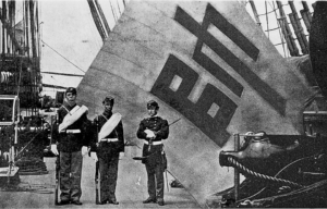 Charles Brown, Hugh Purvis and McLane Tilton standing in front of a captured Korean flag