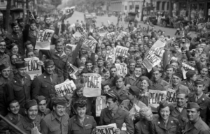 American servicemen and Parisians holding up newspapers in celebration of the Japanese surrender