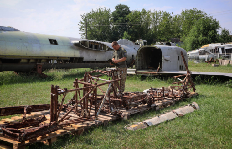 Member of the Armed Forces of Ukraine making notes near the rusty fuselage of a Hawker Hurricane