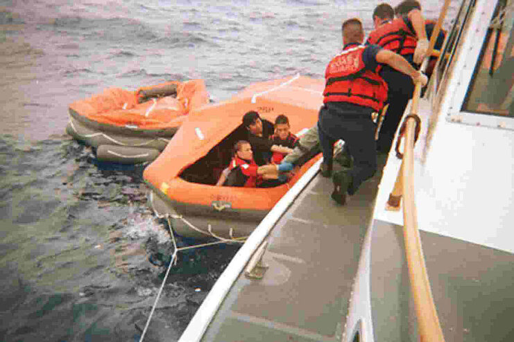 US Coast Guard personnel pulling Japanese crewmen aboard a vessel