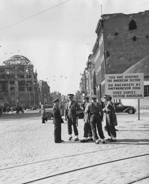 Five American military police officers standing in the middle of a street