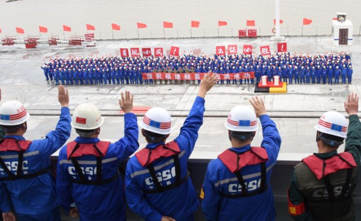 Crowd waving at a group of people aboard the flight deck of the Type 003 Fujian