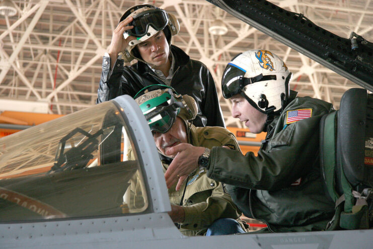 Adam Klein showing Darrell Powers the interior of a McDonnell Douglas F/A-18C Hornet while another airman watches