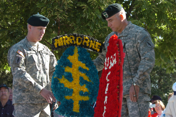 Major General Thomas Csrnko (right) and another man place a wreath beside a memorial of the First Special Forces logo.