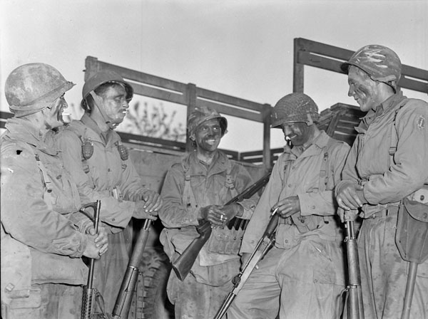 5 Men of the First Special Services Force standing in front of a truck, talking. Black and white. 