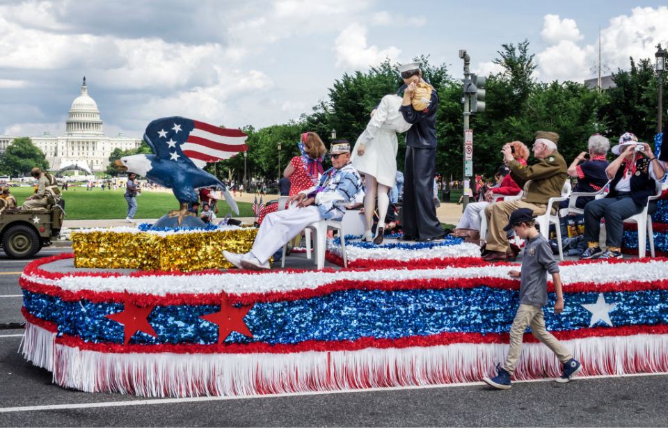 Male child running alongside a parade float that's driving past the White House