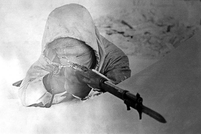 Simo Häyhä in camouflage pointing a sniper rifle. 