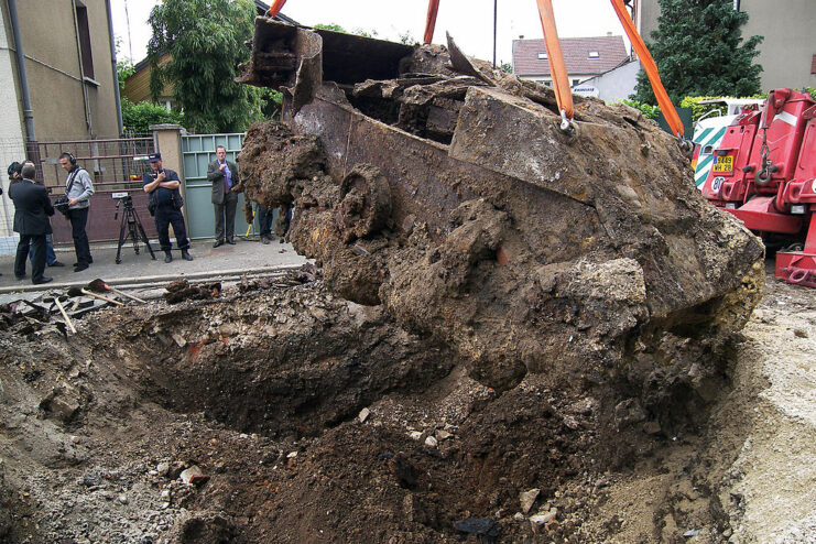 Mechanical digger lifting a mud-caked M5 Stuart from a hole in the ground