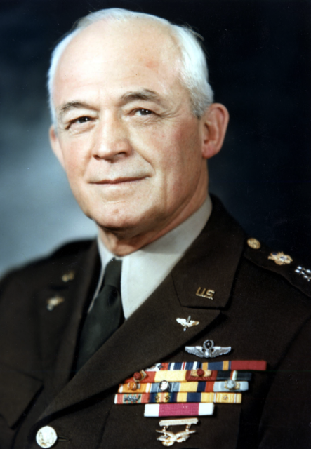 Portrait of man in Air Force uniform smiling in front of a blue and black background. 