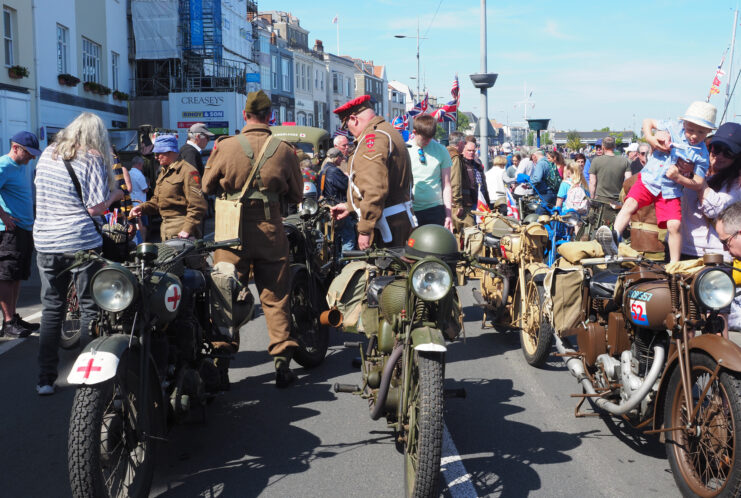 Crowd gathered around military motorcycles in the middle of a street