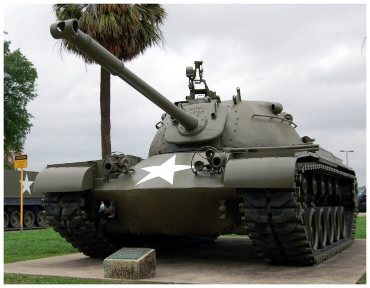 M48 Patton tank in green with white star on the front. Front side. Palm tree in background. 