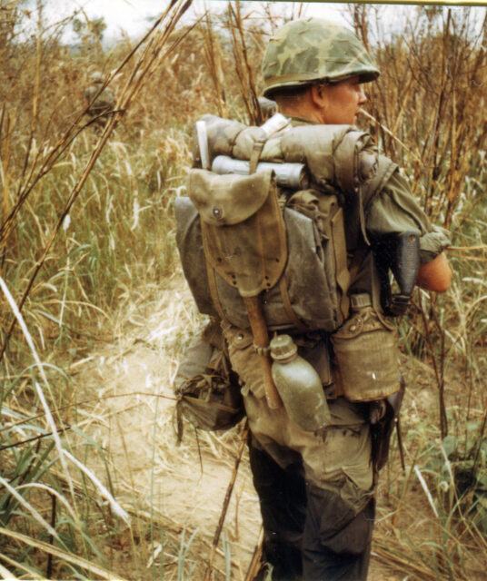 US Navy hospital corpsman walking through tall grass