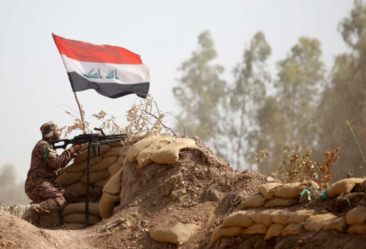 Iraqi soldier aiming a rifle over a makeshift wall