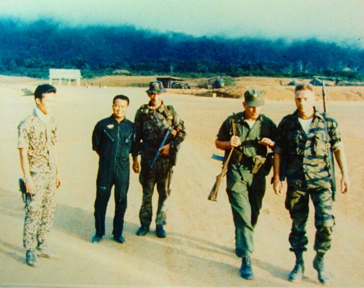 Lauri Törni walking with four other men in the middle of a sandy area