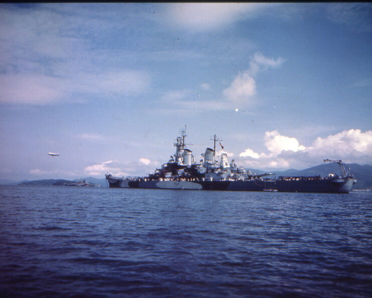 USS Missouri (BB-63) leaving port, with the USS Alaska (CB-1) transiting in the distance