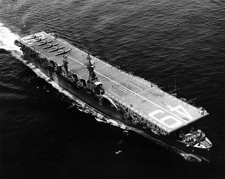 Black and white. Top down view of USS Wright in water. 