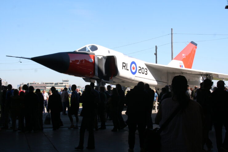 Silhouette of people standing in front of a replica of the Avro Arrow. 