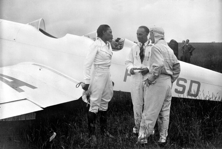 Josephine Baker speaking with two men outside of an aircraft. 