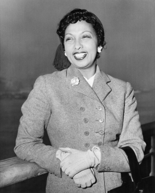 Josephine Baker smiling and leaning on a railing.