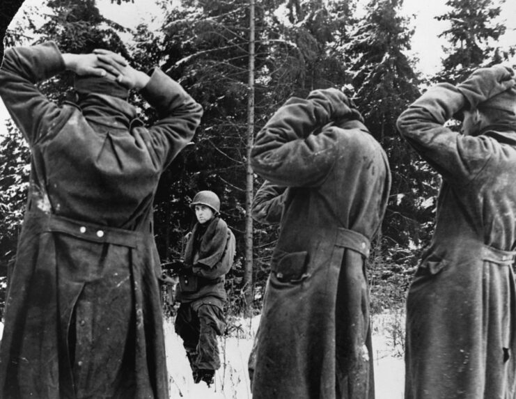 American soldier guarding three captured German soldiers. 