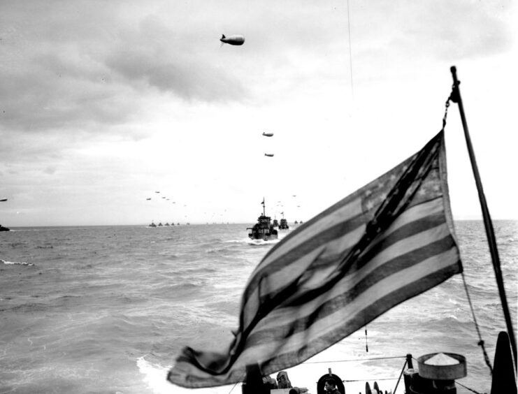 Ships at sea, with the American flag in the foreground