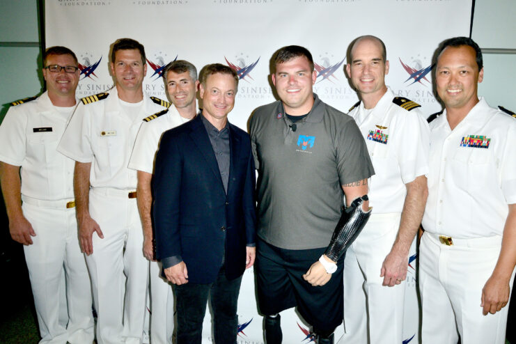 Actor Gary Sinise standing with servicemen at a movie screening. 