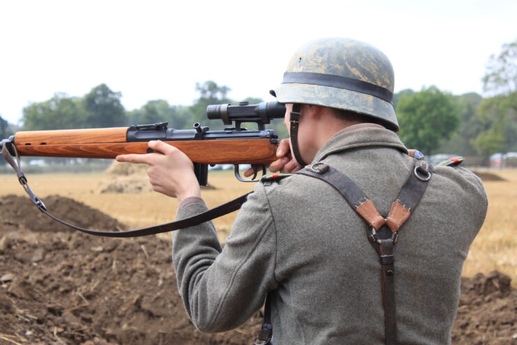 Man wearing a German military uniform and aiming a Gewehr 43