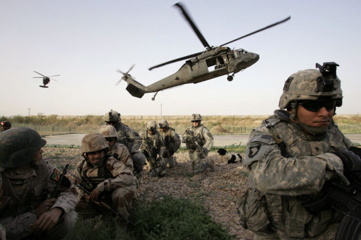 American and Iraqi soldiers walking away from a helicopter hovering overhead