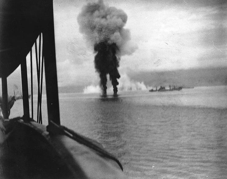 Smoke rising from the ocean, with a ship in the background