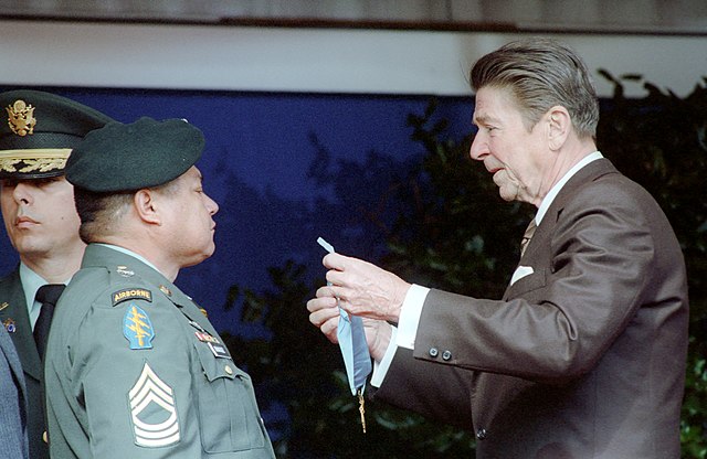 Ronald Reagan holding out the Medal of Honor before Roy Benavidez
