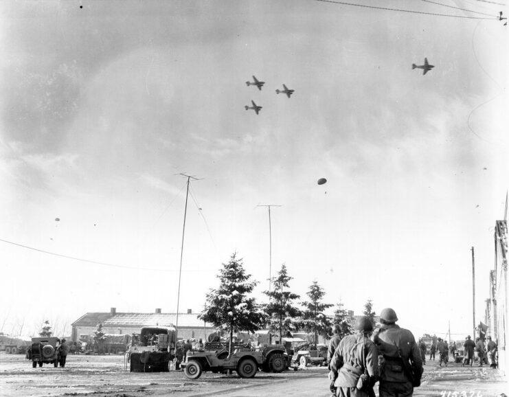 101st Airborne Division paratroopers looking up at Douglas C-47 Skytrains flying overhead